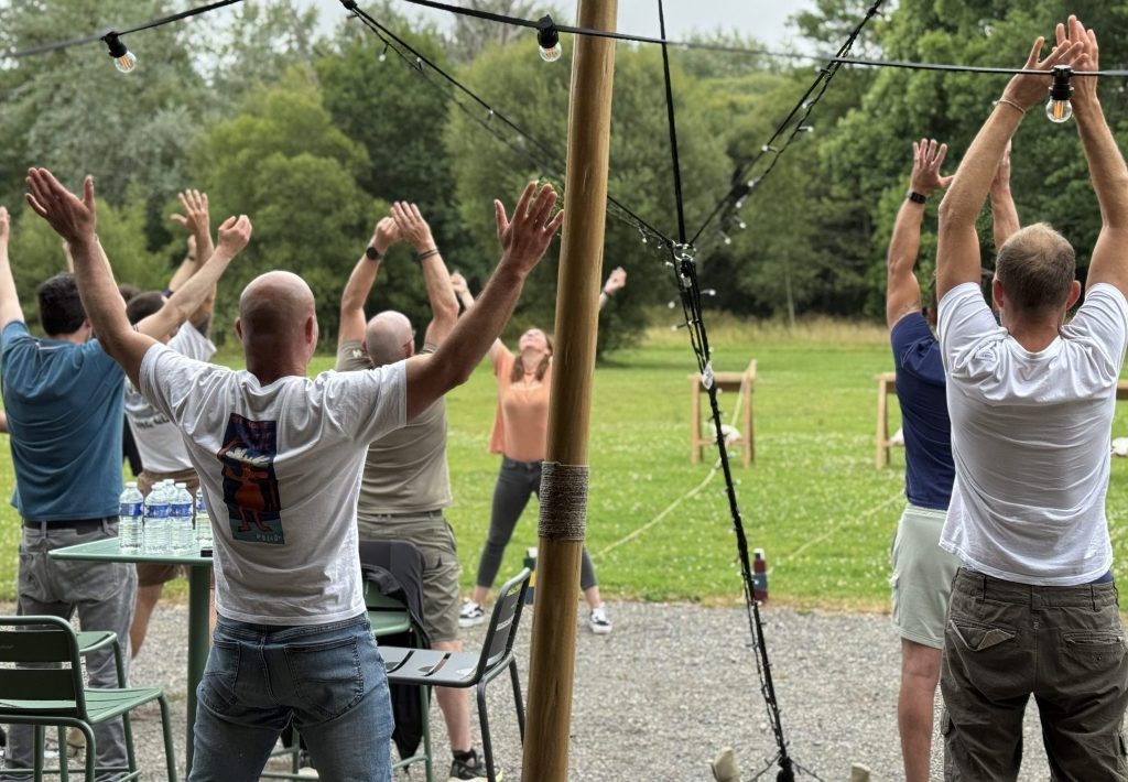 Groupe de salariés participant à un réveil musculaire collectif animé en extérieur.